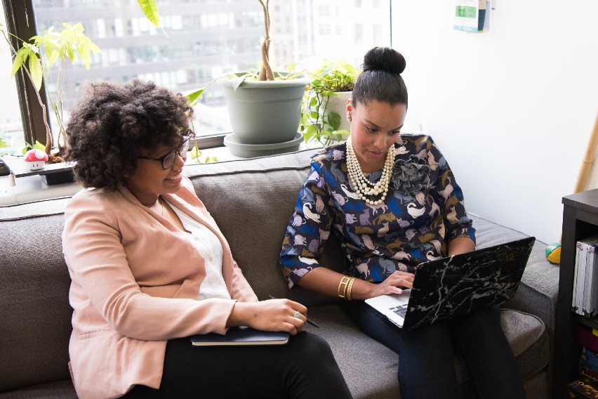 accountant and client on sofa viewing shared laptop screen